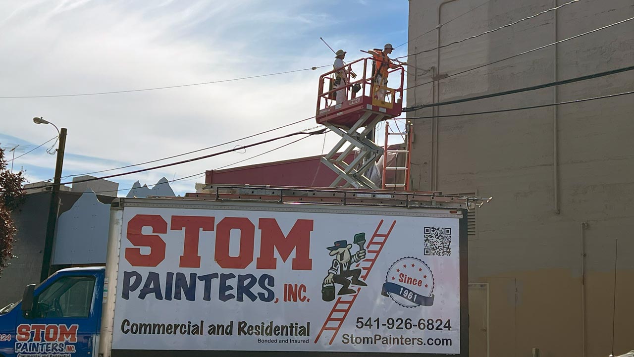 Stom Painters crew using a lift to repaint a commercial building exterior in downtown Albany, Oregon